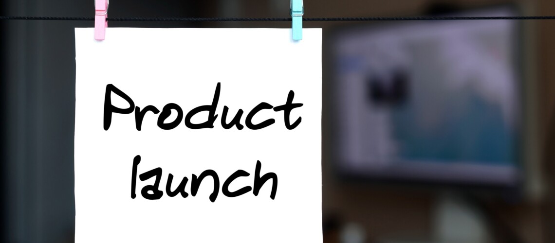 Product launch. Note is written on a white sticker that hangs with a clothespin on a rope on a background of office interior