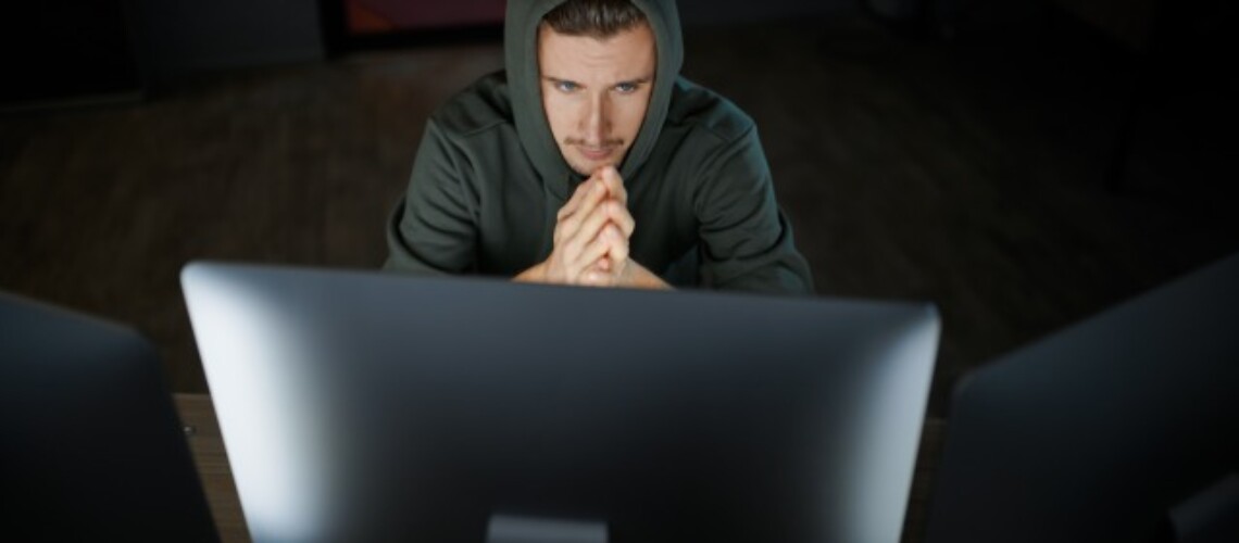 serious-male-hacker-in-hood-works-on-computer-MX9EL9B-2